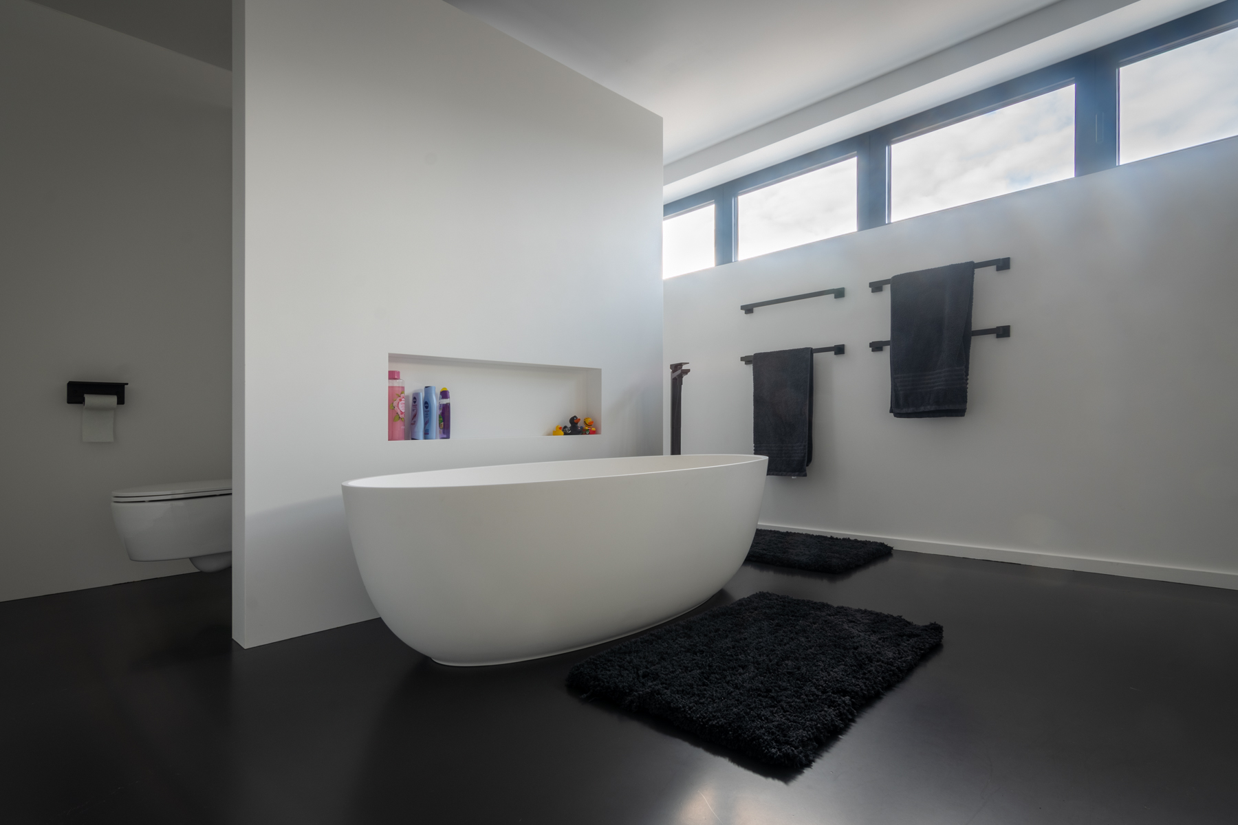 Moderne, witte badkamer met zwarte vloer.