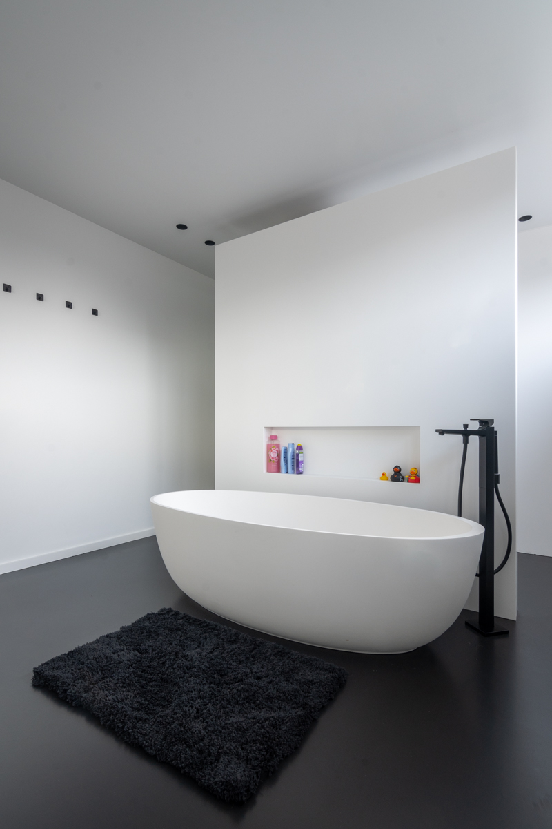 Moderne badkamer met zwarte gietvloer en Corian T-wand.